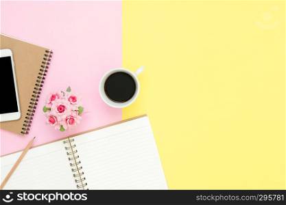 Office desk working space - Flat lay top view of a working space with white blank notebook page, coffee cup and mock up phone on pastel background. Pastel pink yellow color background space concept.