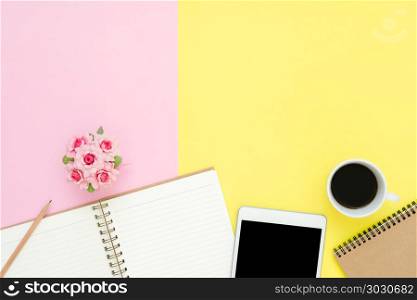 Office desk working space - Flat lay top view photo of working s. Office desk working space - Flat lay top view photo of working space with blank mock up tablet, coffee cup and notebook on pastel background. Pastel pink yellow color copy space working desk concept.