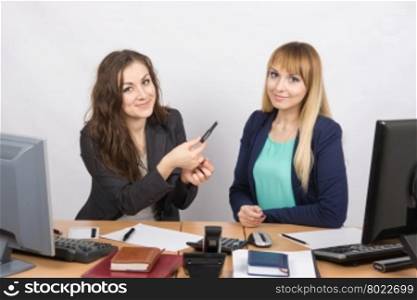 Office girl sitting next to a colleague offers lipstick