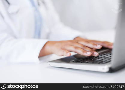 office, health, medicine, technology and internet concept - female doctor using her laptop computer