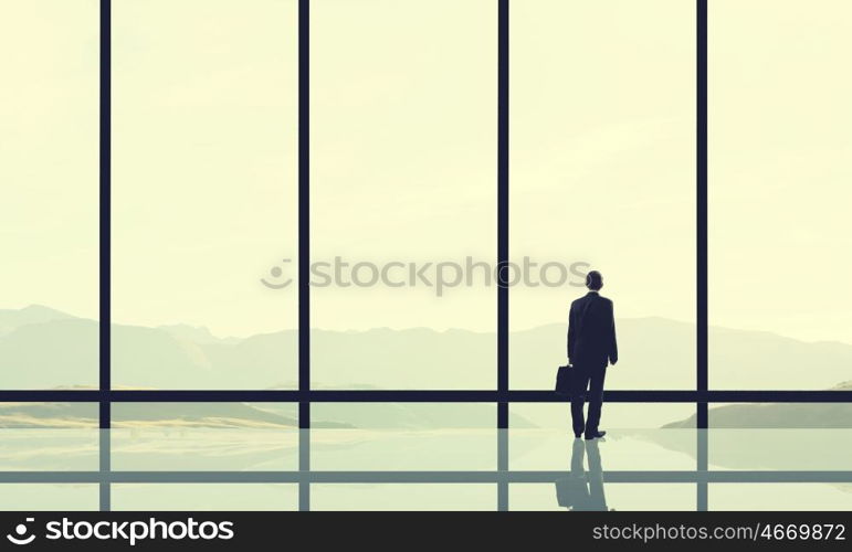 Office life. Businessman standing with back and looking in office window