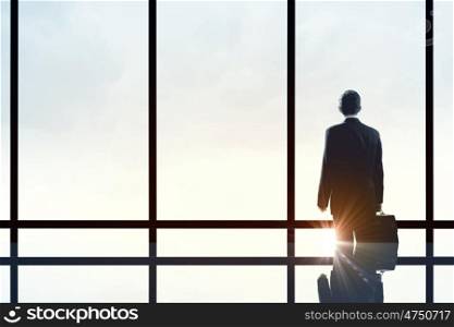 Office life. Businessman standing with back and looking in office window