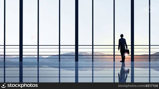 Office life. Businessman standing with back and looking in office window