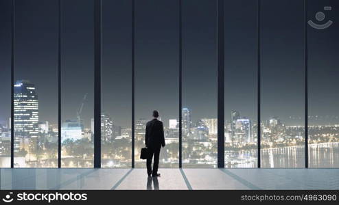 Office life. Businessman standing with back and looking in office window