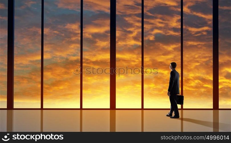 Office life. Businessman standing with back and looking in office window