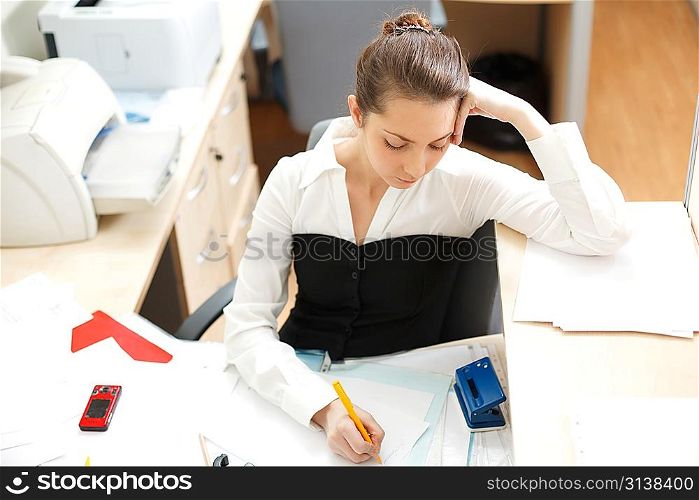 Office life. Young woman writing something at paper