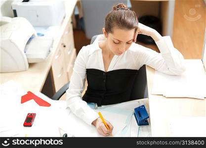 Office life. Young woman writing something at paper