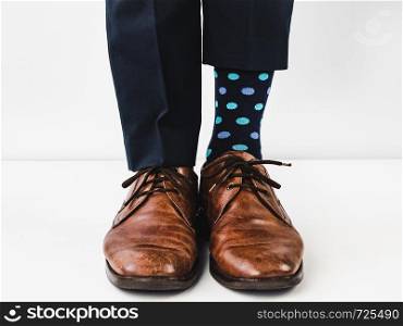 Office manager standing in stylish shoes, blue pants and bright, colorful socks on a white, isolated background. Close-up. Studio photo. Concept of lifestyle, fun and elegance. Office Manager in stylish shoes and bright socks