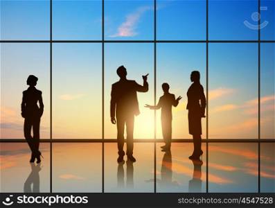 Office meeting. Silhouettes of businesspeople standing against panoramic office window