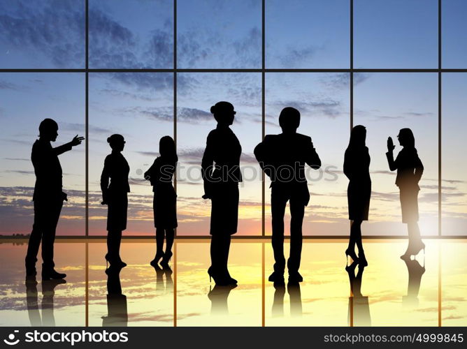 Office meeting. Silhouettes of businesspeople standing against panoramic office window