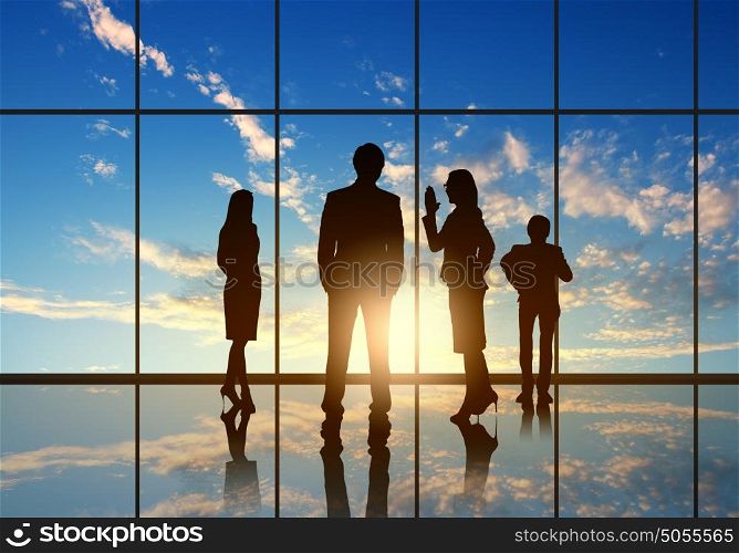 Office meeting. Silhouettes of businesspeople standing against panoramic office window