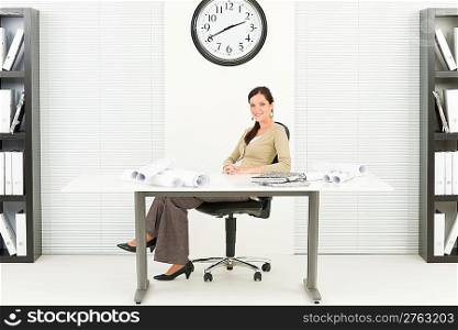 Office professional architect female with blueprints sitting behind table