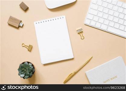 Office stationery on a beige background. Pen, Notepad, paper clip, usb drive, computer. Workplace top view
