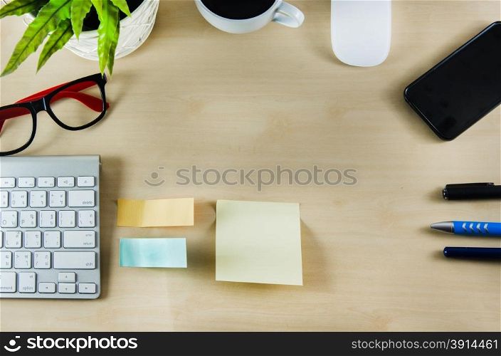 Office supplies and coffee cup on wood table. View from above