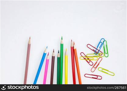 Office supplies concepts, Colored crayon pencils and clips on white background with wide banner, brochure, poster design template with copy space. Top view, Closeup.