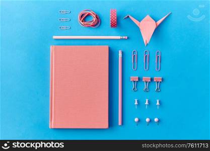 office supplies, stationery and object concept - pink notebook, pins, clips and pencils on blue background. pink notebook, pins, clips, pencils and rubbers