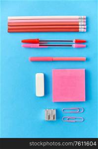 office supplies, stationery and object concept - pink sticky notes, clips, pens with pencils and eraser on blue background. pink sticky notes, pens, pencils, clips and eraser
