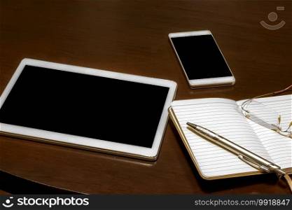 Office table  mobile phone, tablet, glasses, notebook and pen with copy space. Gadgets on a wooden table.  