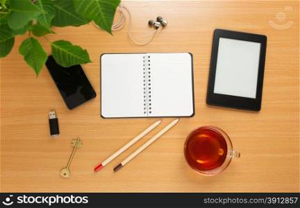 Office table with notepad, tea cup , pen , smartphone , headphone, tablet. View from above