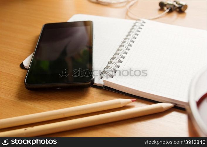 Office table with notepad, tea cup , pen , smartphone , headphone. View from above