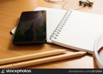 Office table with notepad, tea cup , pen , smartphone , headphone. View from above