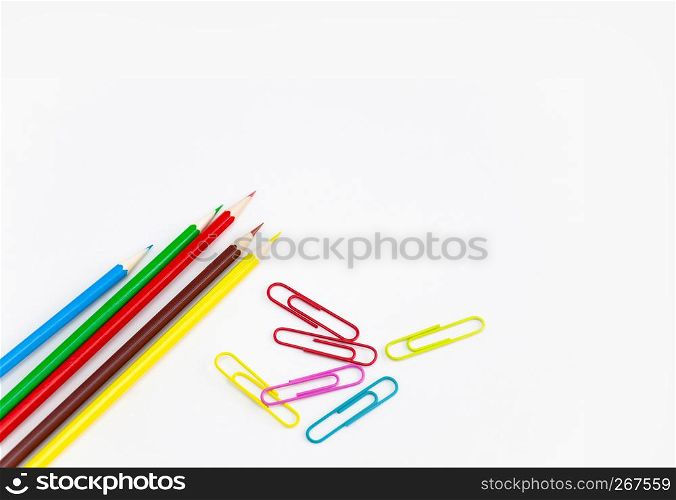 Office utensils supplies concepts, Colorful crayon pencils and multi-colored clips on white background with copy space. View from above.