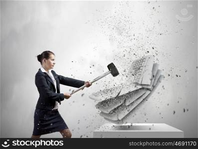 Office work. Businesswoman in anger crashing keyboard with hammer