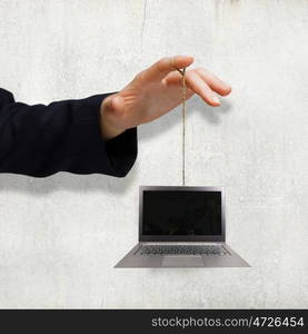 Office work. Close up of business person hand holding laptop on rope