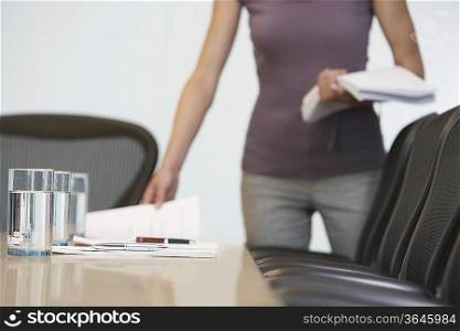 Office worker arranging documents on conference table, mid section