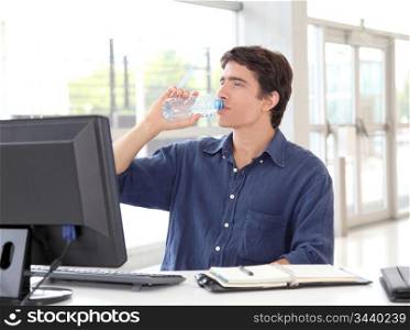 Office worker drinking water in front of desktop computer