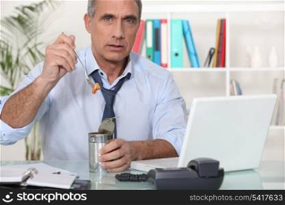 Office worker eating from tin can