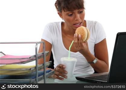 Office worker having a quick lunch in front of her computer