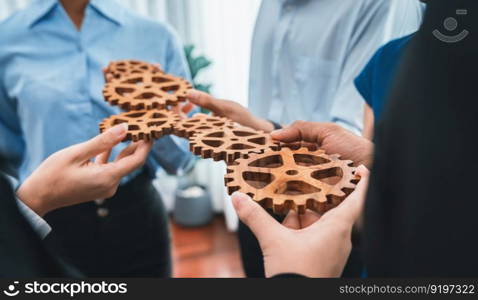 Office worker holding cog wheel as unity and teamwork in corporate workplace concept. Diverse colleague business people showing symbol of visionary system and mechanism for business success. Concord. Office worker holding cog wheel as unity and teamwork in workplace. Concord