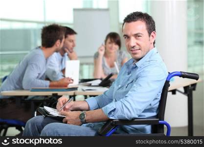 Office worker in a wheelchair with colleagues in the background