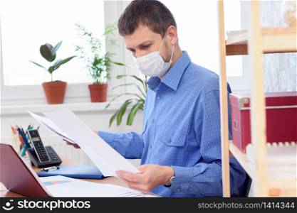 Office worker in protective medical mask works with documents in the office