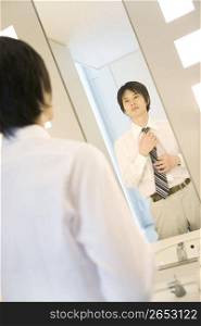 Office worker putting on a necktie in rest room