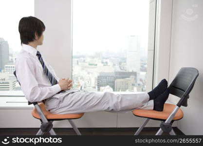 Office worker taking a break with stretching his foot on a chair