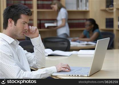 Office worker using laptop in office, side view