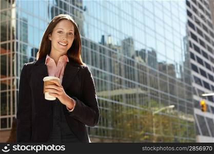 Office worker with drink outside office building portrait