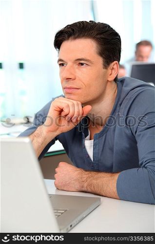 Office worker with exhausted look in front of computer