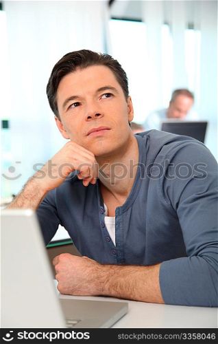 Office worker with exhausted look in front of computer