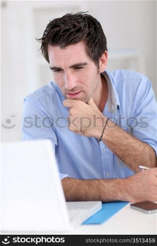 Office worker with thoughtful look in front of laptop