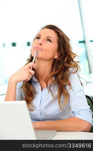 Office worker with toughtful look in front of laptop computer