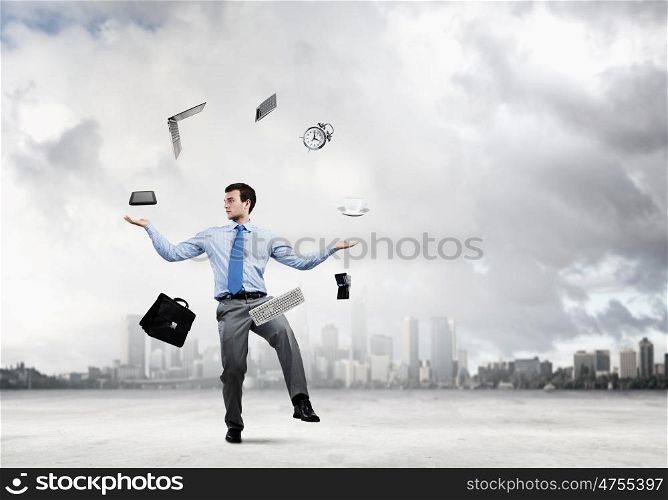 Office worker. Young businessman juggling with business items against urban scene