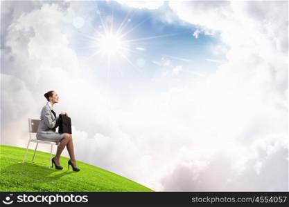 Office worker. Young businesswoman sitting in chair against nature landscape