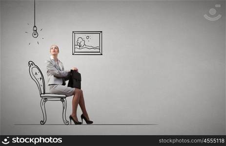 Office worker. Young businesswoman sitting in chair with suitcase in hands