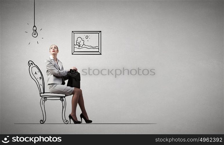 Office worker. Young businesswoman sitting in chair with suitcase in hands