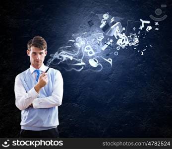 Office worker. Young handsome businessman smoking pipe with business items at background