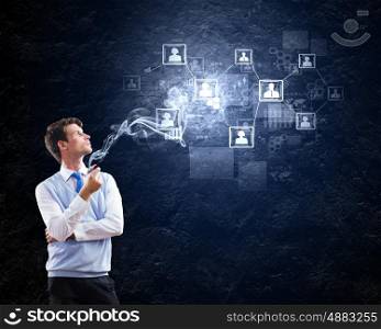 Office worker. Young handsome businessman smoking pipe with business items at background