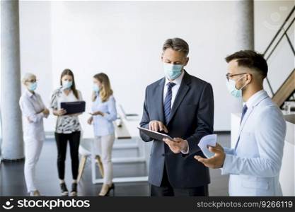 Office workers have a meeting in the office with face masks as a protection from coronavirus